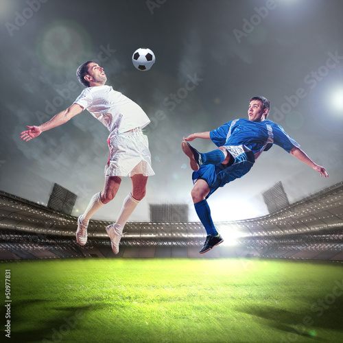Photo: two football players striking the ball two football players striking the ball