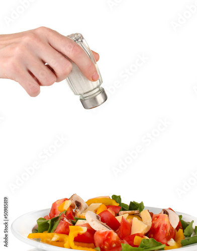 Photo: Hand adding salt using salt shaker isolated on white Hand adding salt using salt shaker isolated on white