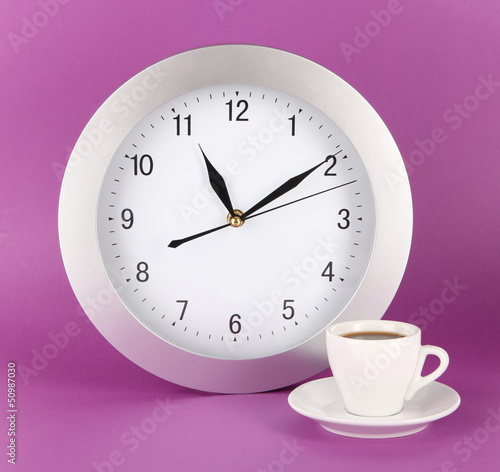 Photo: Cup coffee and clock on purple background Cup coffee and clock on purple background