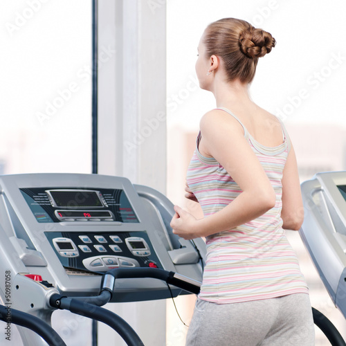 Photo: Woman at gym exercising. Run on machine Woman at gym exercising. Run on machine
