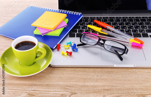 Photo: Laptop with stationery and cup of coffee on table Laptop with stationery and cup of coffee on table