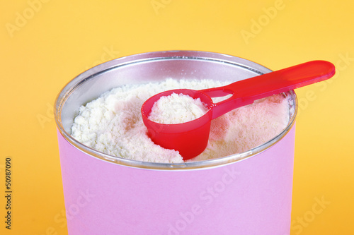 Photo: Powdered milk for baby on yellow background Powdered milk for baby on yellow background
