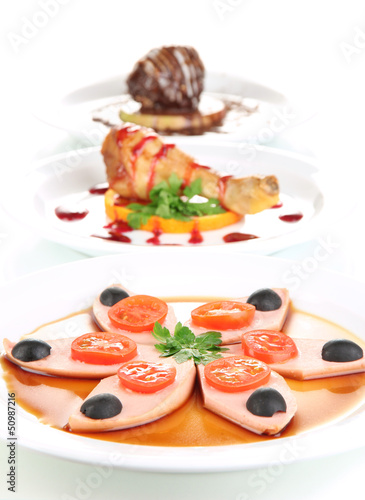 Photo: Small portions of food on big white plates isolated on white Small portions of food on big white plates isolated on white