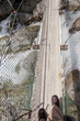 Boots on narrow swing bridge over white water