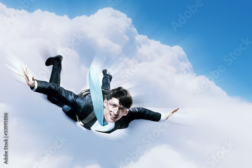 Photo: Young businessman flying with parachute on back Young businessman flying with parachute on back