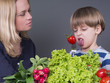 Photo: Mother trying to feed her little son with tomato Mother trying to feed her little son with tomato