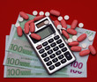 pills, money and calculator on a red background