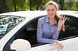 Photo: Pretty female driver in a white car showing the car key Pretty female driver in a white car showing the car key