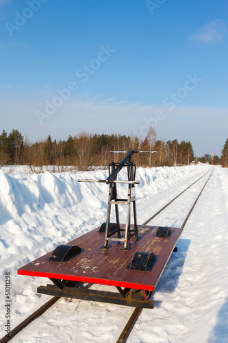 Photo: handcar on a narrow track in snow and blue sky handcar on a narrow track in snow and blue sky