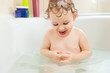 Happy little baby girl bathing in bathtub