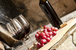 Copas de vino tinto, botella uvas y corcho.