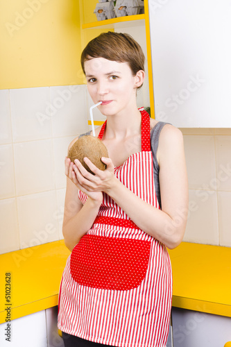 Photo: Woman drinking coconut milk in kitchen Woman drinking coconut milk in kitchen