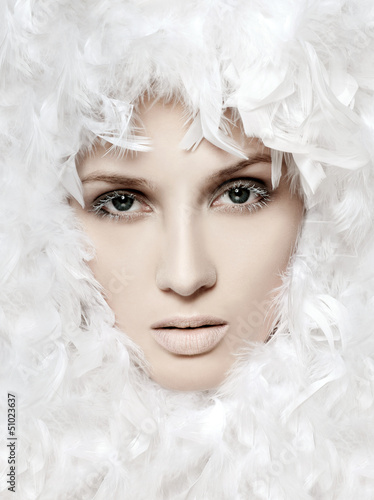 Photo: fashionable woman's face surrounded by white feathers fashionable woman's face surrounded by white feathers