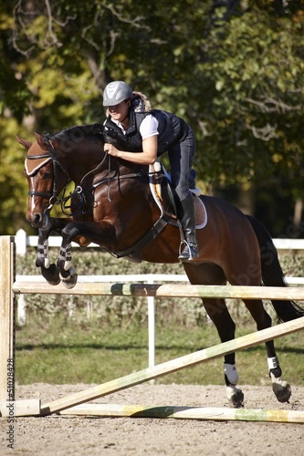 Photo: Horsewoman putting horse over the jumps Horsewoman putting horse over the jumps