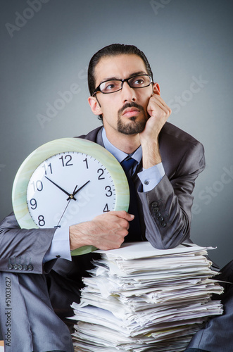 Photo: Man with clock and pile of papers Man with clock and pile of papers