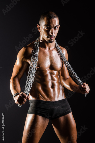 Photo: Muscular man with chain on black background Muscular man with chain on black background