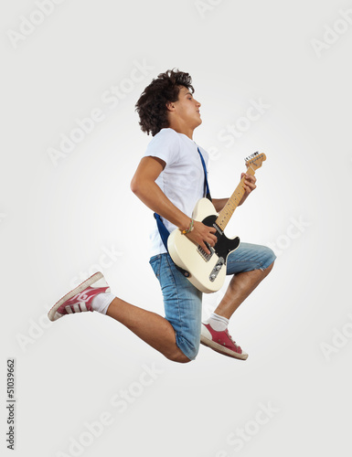 Photo: young man playing on electro guitar and jumping young man playing on electro guitar and jumping