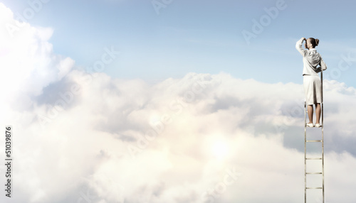Photo: Businesswoman standing on ladder Businesswoman standing on ladder