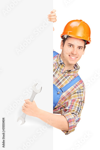 Photo: Young construction worker with helmet posing behind a panel and Young construction worker with helmet posing behind a panel and