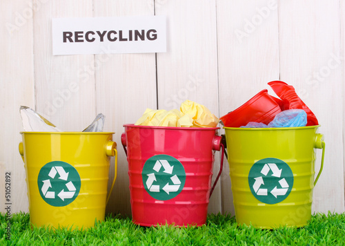 Photo: Recycling bins on green grass near wooden fence Recycling bins on green grass near wooden fence