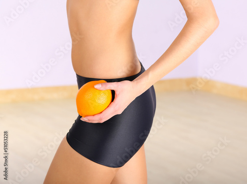 Photo: Beautiful female figure with orange on light background Beautiful female figure with orange on light background