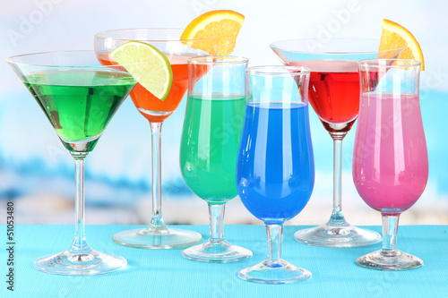 Photo: Glasses of cocktails on table near pool Glasses of cocktails on table near pool