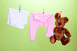 Baby clothes hanging on clothesline, on color background