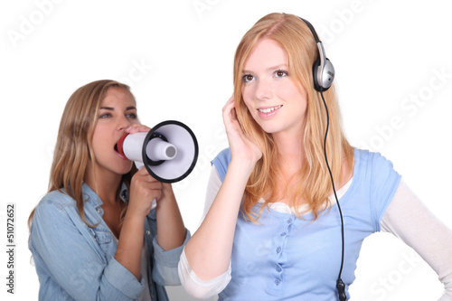 Photo: girl listening to music and friend shouting in loudspeaker girl listening to music and friend shouting in loudspeaker