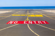 no entry sign at the runway of the airport with ocean in backgro