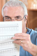 Man in glasses reading a printed sheet