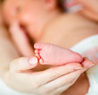 mother's hand holding small baby's foot