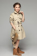 Lovely girl wearing beige trench coat holding handbag