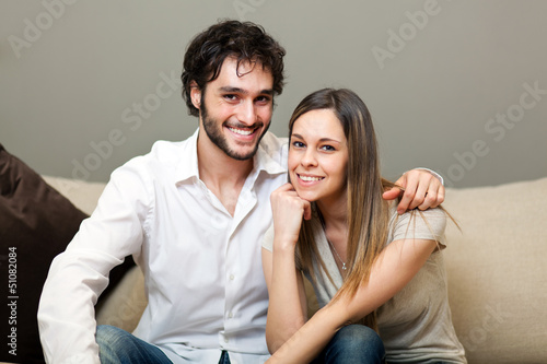 Photo: Portrait of a lovely young couple sitting on the couch Portrait of a lovely young couple sitting on the couch