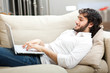 Portrait of a relaxed young guy using laptop at home