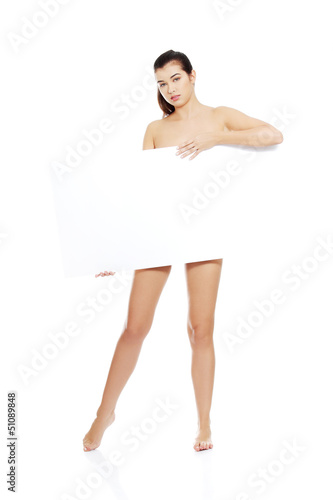 Photo: Sexy naked brunette holding empty board. Sexy naked brunette holding empty board.