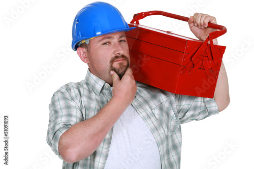 Photo: craftsman holding a tool box and touching his chin craftsman holding a tool box and touching his chin
