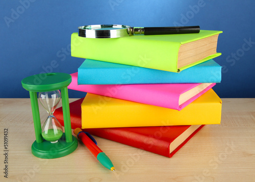 Photo: color books with magnifying glass on table on blue background color books with magnifying glass on table on blue background