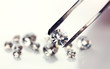 Beautiful shining crystal (diamond) in the tweezers, isolated