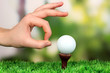 Hand pushing golf ball on green grass outdoor close up