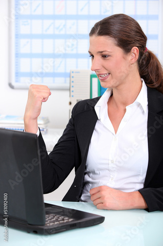Photo: businesswoman delighted with what she can see on her computer businesswoman delighted with what she can see on her computer