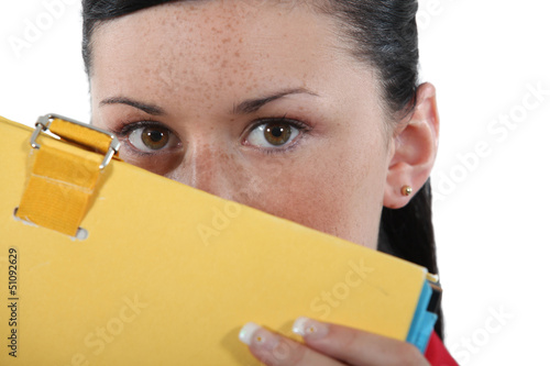 Photo: Shy woman hiding behind folder Shy woman hiding behind folder