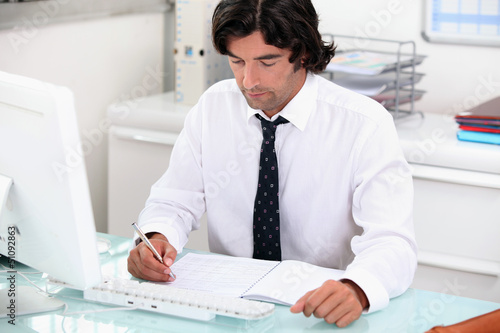 Photo: manager in his office with laptop manager in his office with laptop