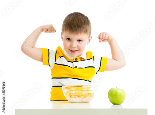 Photo: kid boy eating healthy food and showing strength kid boy eating healthy food and showing strength