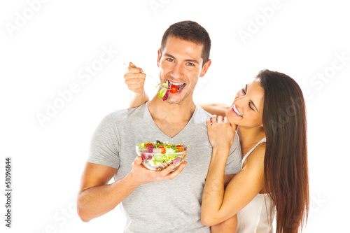Photo: Happy couple eating salad together on a white background Happy couple eating salad together on a white background