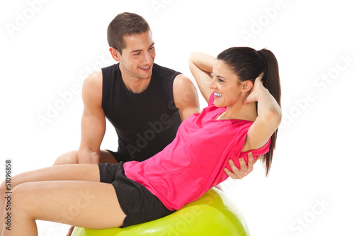 Photo: Woman with her personal trainer doing exercises on fitness ball Woman with her personal trainer doing exercises on fitness ball