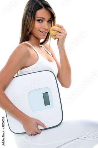 Photo: young and thin woman with an apple and a bathroom scale young and thin woman with an apple and a bathroom scale