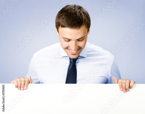Photo: Business man showing blank signboard, on violet Business man showing blank signboard, on violet
