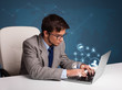 Young man sitting at desk and typing on laptop with social netwo
