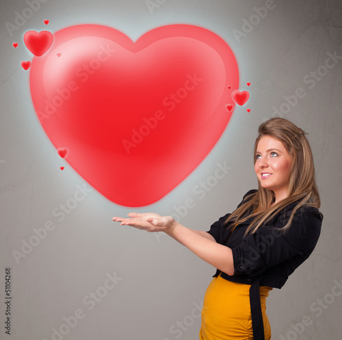 Photo: Young lady holding lovely 3d red heart Young lady holding lovely 3d red heart