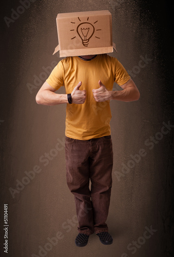 Photo: Young man gesturing with a cardboard box on his head with light Young man gesturing with a cardboard box on his head with light